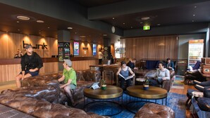 A lobby with leather sofas, round tables, and a reception desk. - Bunk Backpackers (Fortitude Valley)