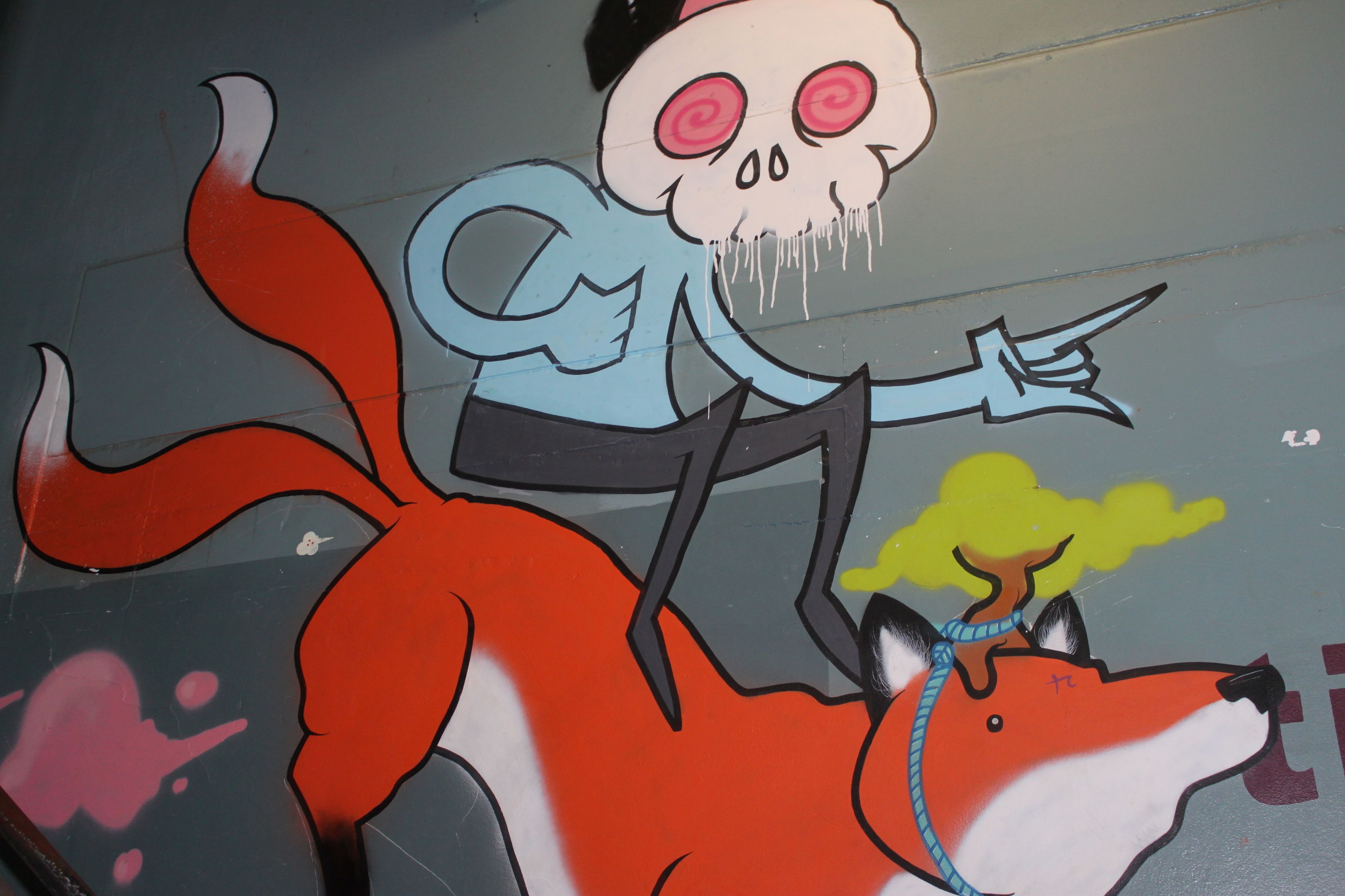 Paredes com grafite de um personagem de desenho animado montando uma raposa.