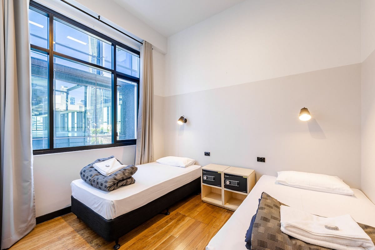 Una habitación de hotel moderna con un ventanal grande, una cama, una mesita de noche y un armario.
