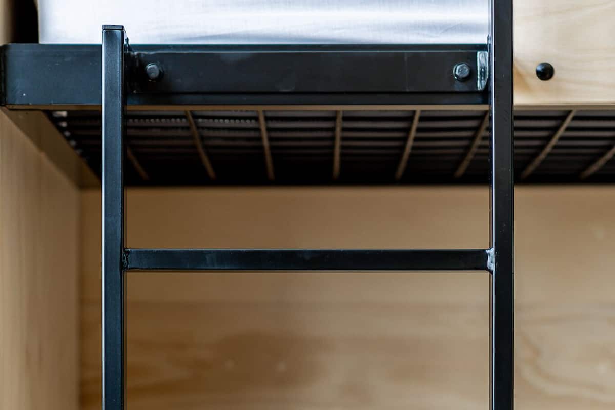 Una cama litera con estructura metálica y cabecera de madera.