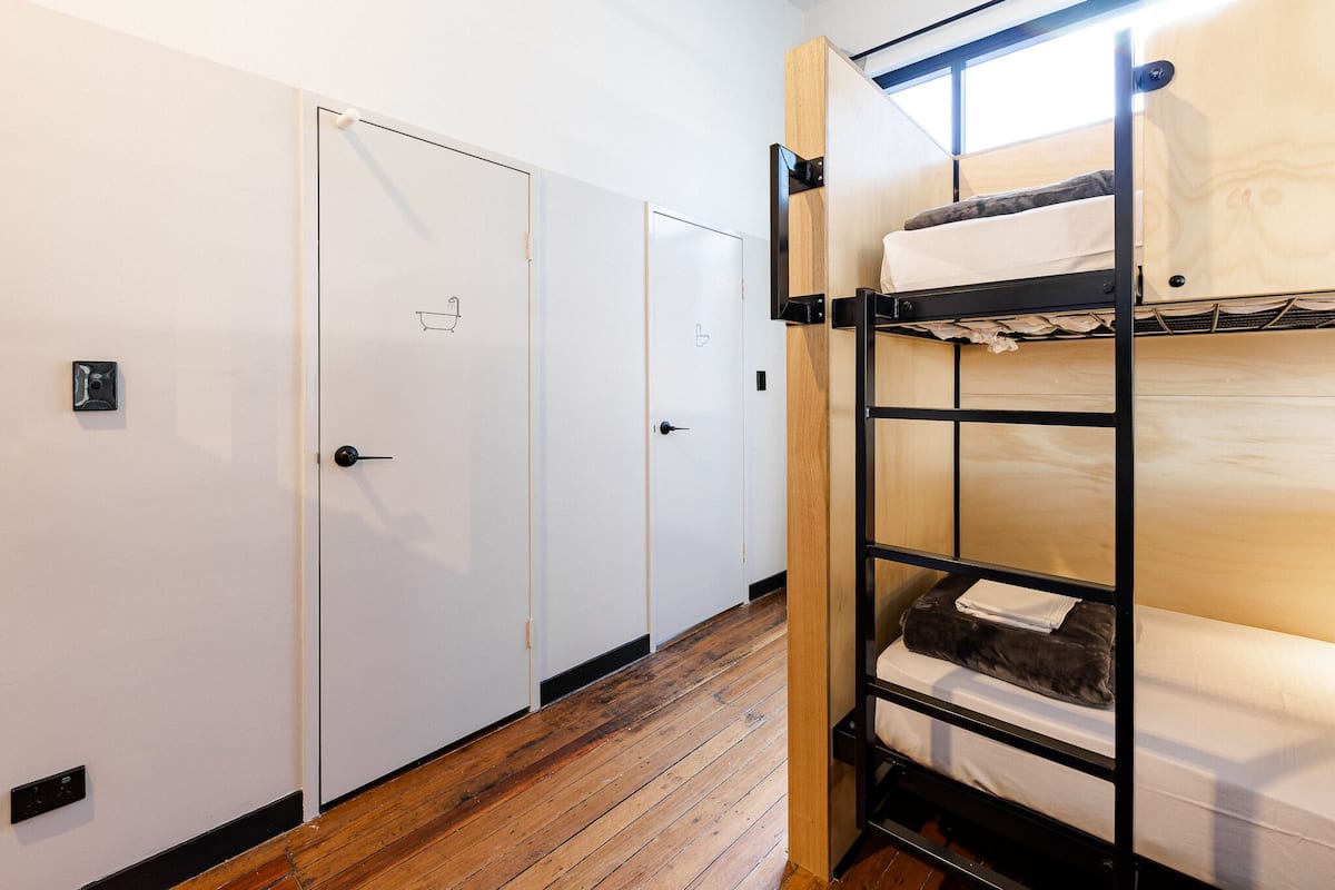 Habitación con literas, suelo de madera y paredes blancas.