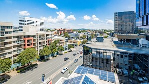 A cityscape with modern buildings, a clear sky, and a road with vehicles. - Bunk Backpackers (Fortitude Valley)
