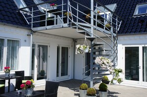 A modern outdoor area with a spiral staircase, potted plants, and outdoor furniture. - Hotel Coco Aps (Esbjerg)