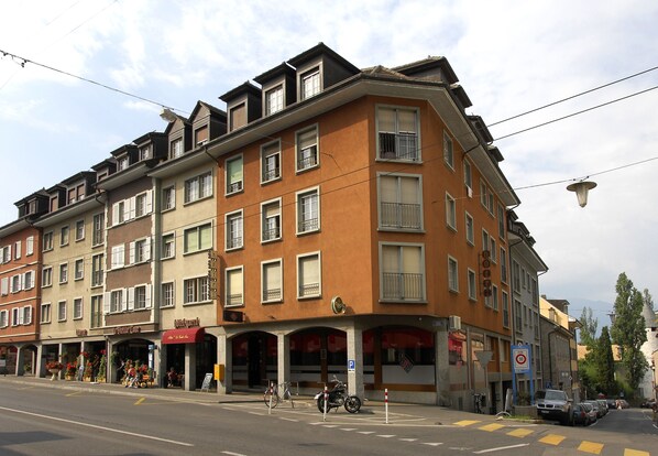 Um hotel de vários andares com entrada na esquina, área de estar ao ar livre e espaço para bicicletas.
