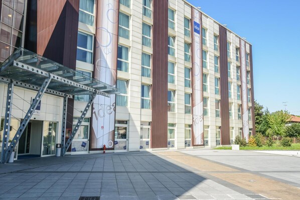 Un hotel moderno con entrada de vidrio, varios pisos y un llamativo letrero que dice 'Idea Hotel'.