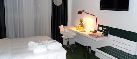 A hotel room with two beds, a desk, a chair, a TV, and a trash can.