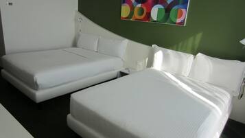 Une chambre d’hôtel avec deux lits simples, une petite table de chevet et un tableau abstrait aux couleurs vives accroché au mur.