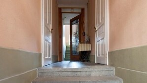 A hallway with a welcome mat at the bottom of the stairs leading to a door.