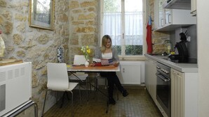 A kitchen with stone walls, a dining table with chairs, a window, and a stove.