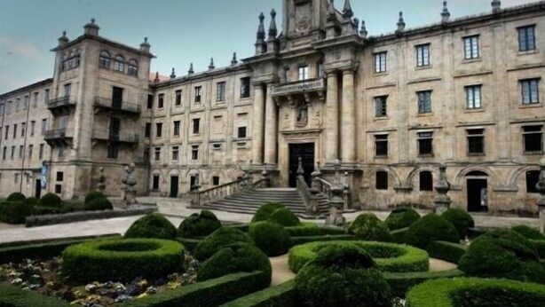 A historic building with a grand entrance, symmetrical facade, and formal garden.