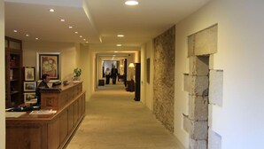 A hotel lobby with a reception desk, a stone accent wall, and a corridor leading to other areas.