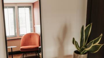 Une pièce avec un grand miroir qui reflète une chaise et une plante en pot.