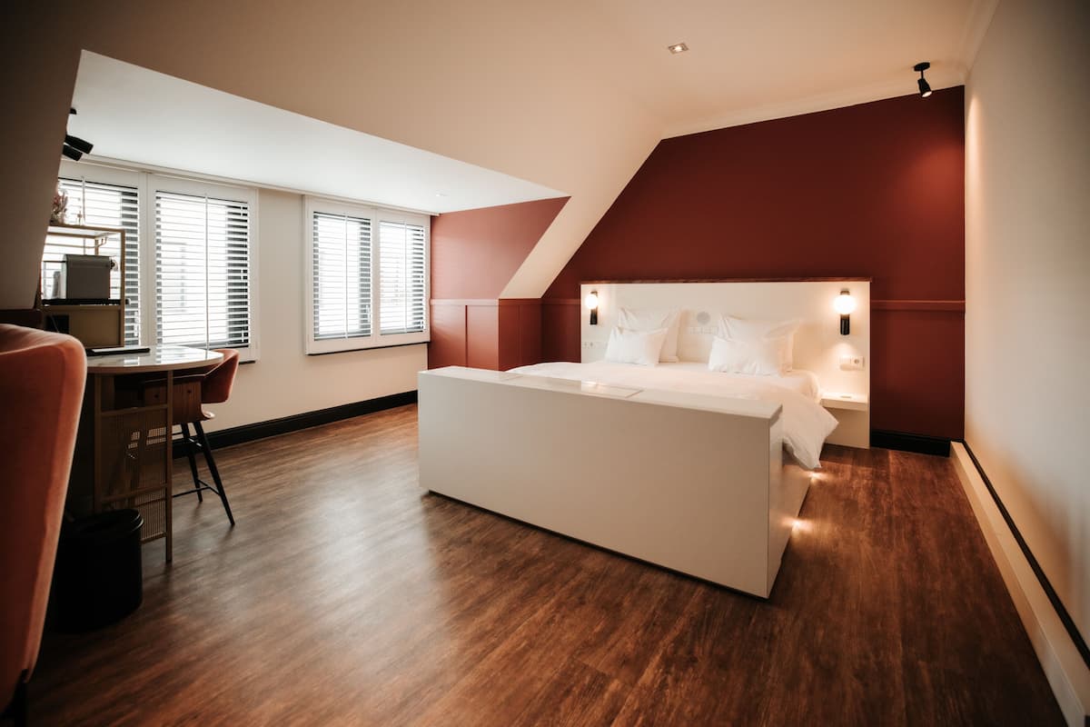 A modern bedroom with a large bed, a desk, and a chair.