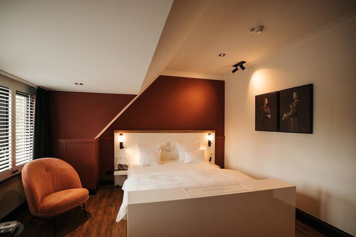 A modern hotel room with a large bed, a chair, and a desk.