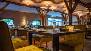 Een restaurant met gedekte tafels, met een modern interieur, houten balken en hanglampen.