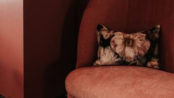 A corner of a room with a red wall and a red sofa with a floral pillow.