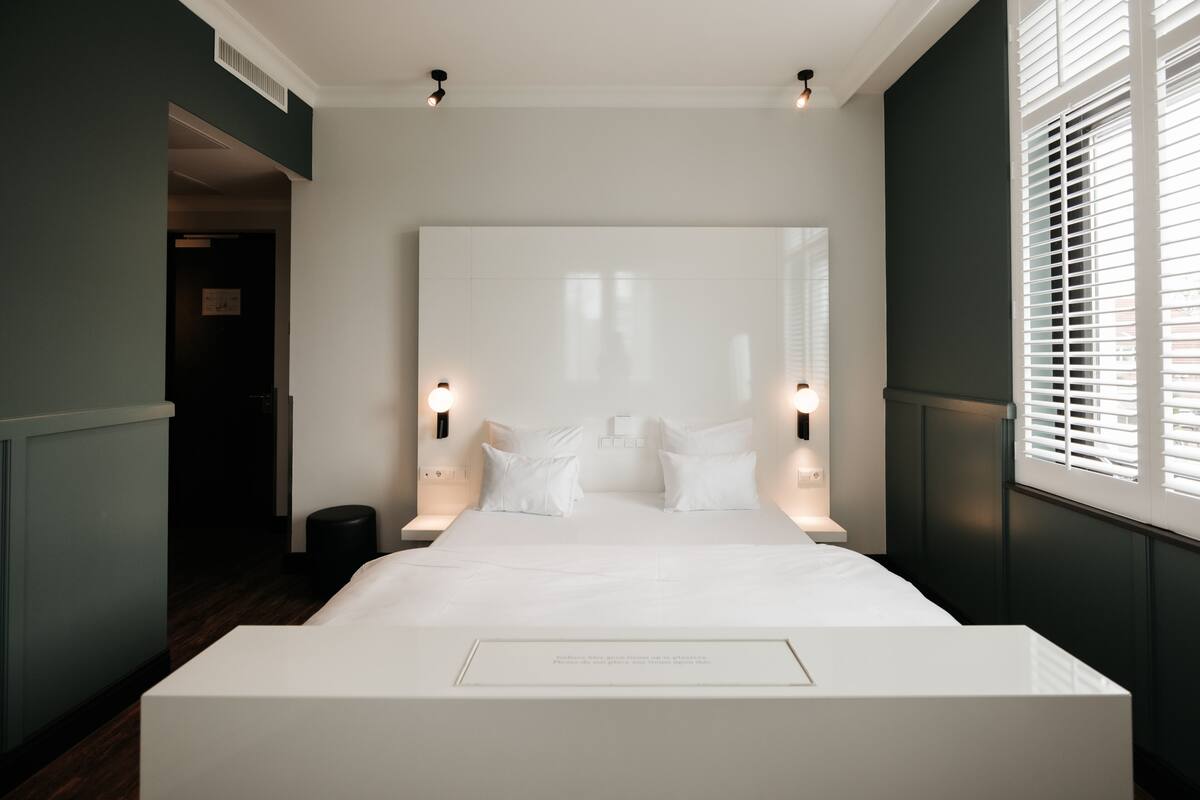 A modern bedroom with a large bed, two bedside tables, and a wall-mounted light fixture.