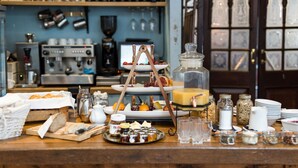 Buffet de café da manhã com diversos alimentos, máquina de café e garrafas de vinho em prateleiras.
