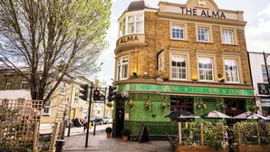 Edifício de esquina com toldo verde e a fachada com o nome "The Alma".