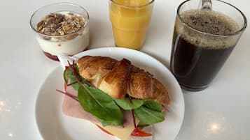 Un plato con un sándwich, un vaso de jugo y un vaso de refresco.