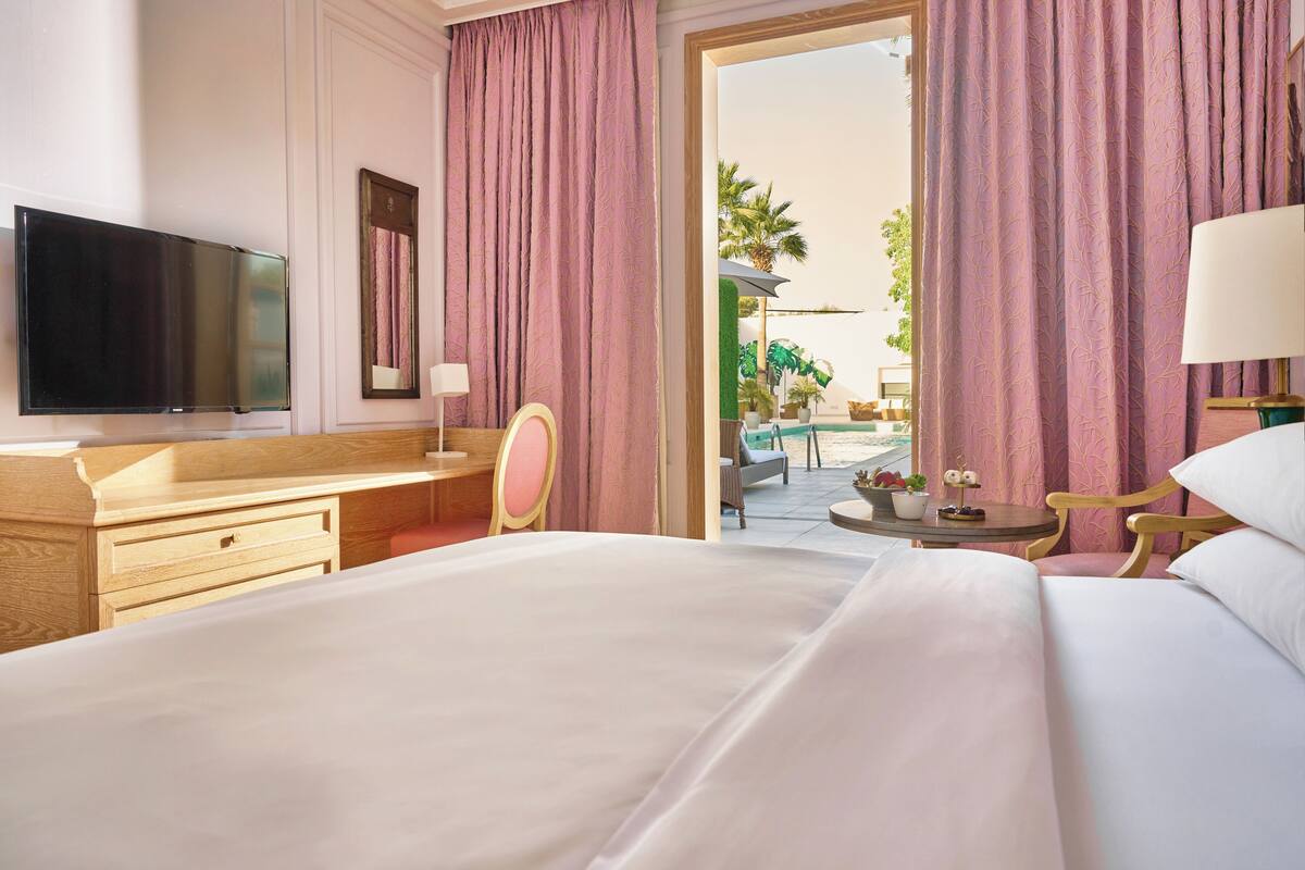 Une chambre d’hôtel équipée d’un lit, d’un bureau, d’une chaise, d’une télévision et offrant une vue sur l’extérieur.