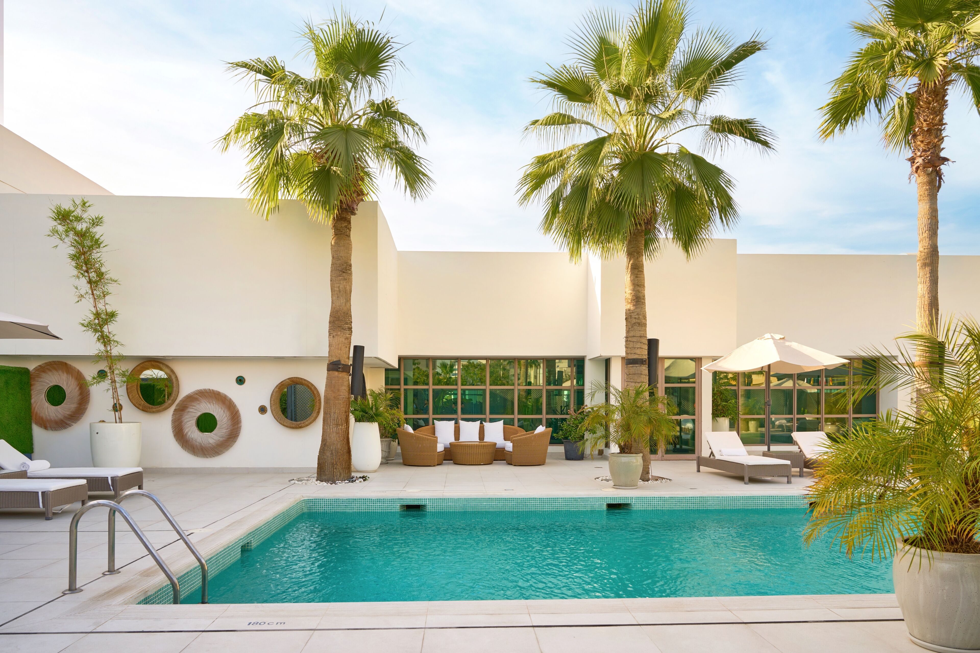 A poolside area with lounge chairs, a seating area, and palm trees.