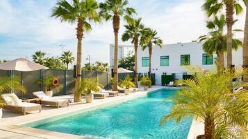 Una piscina al aire libre, sillones reclinables de piscina