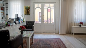 A well-lit living room with a glass coffee table, a leather armchair, and a bookshelf. - Sultanahmet Cesme Hotel (Istanbul)