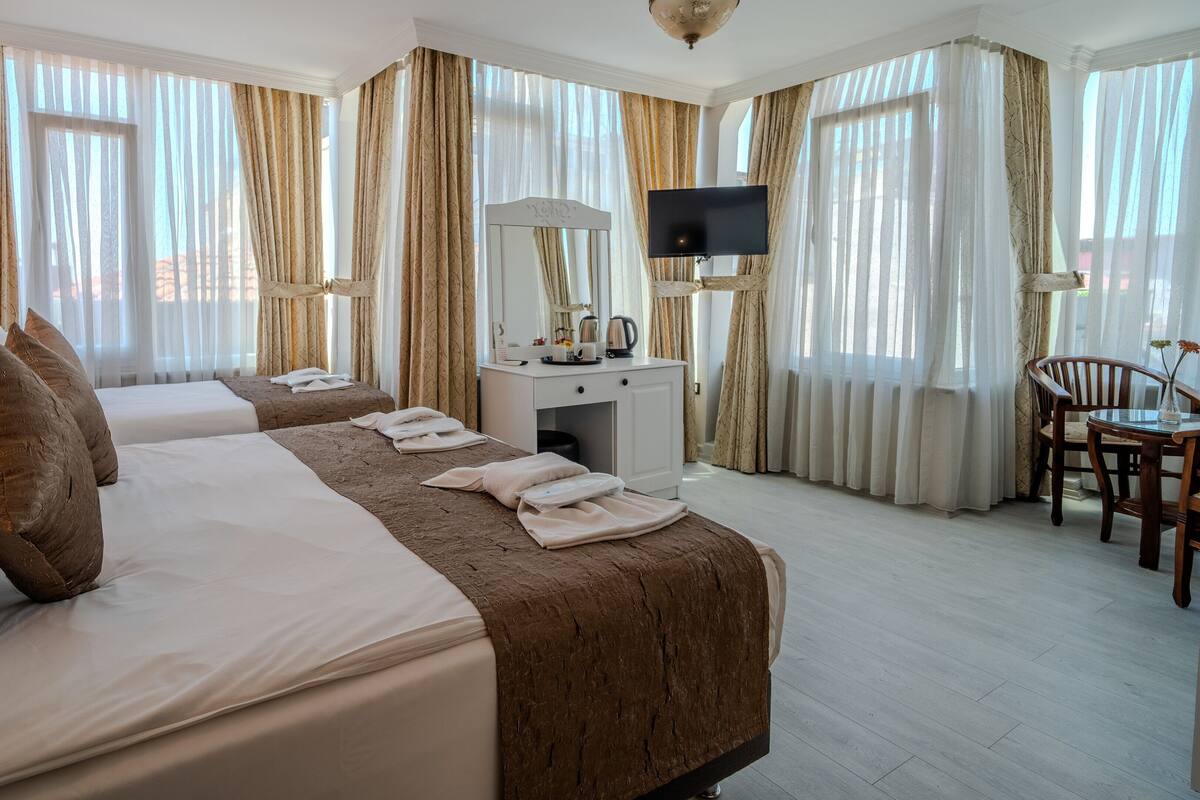 A hotel room with two beds, a desk with a TV, and a chair.