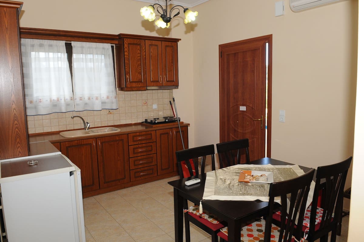 A kitchen with wooden cabinets, a refrigerator, a sink, and a dining table with chairs.