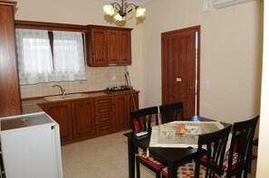 A kitchen with wooden cabinets, a refrigerator, a sink, and a dining table with chairs.