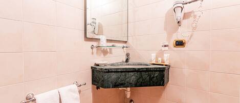 A bathroom with a marble sink, a hairdryer, a towel rack, and a toilet.