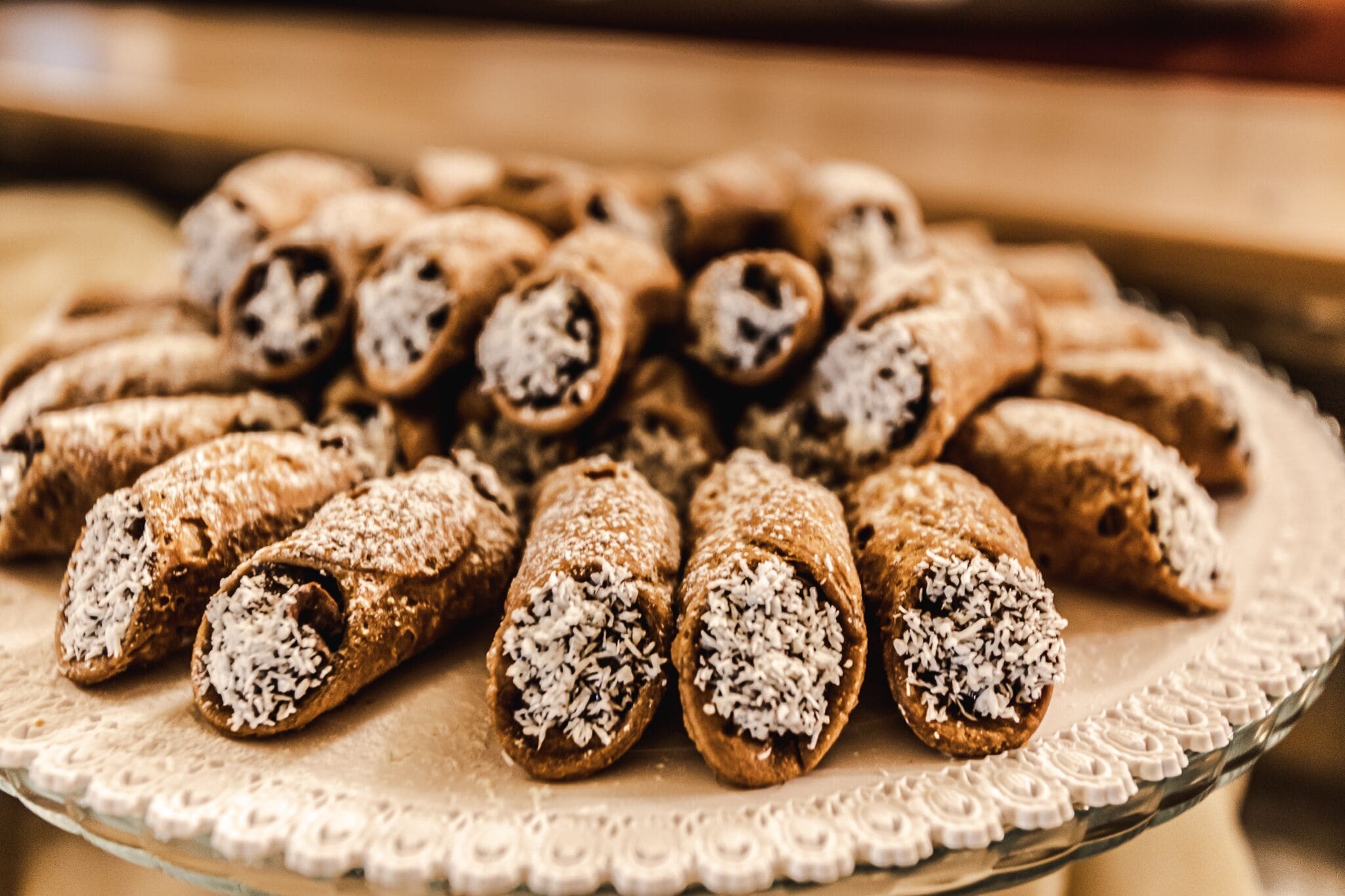 A plate of rolled desserts with coconut on a lace doily.