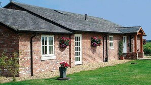 A brick house with a sloped roof, white-framed windows, and flower boxes on the exterior walls. - New Farm Bed & Breakfast (Winsford)