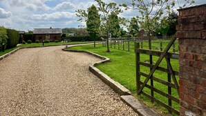 A gravel driveway leading to a brick wall with a wooden fence. - New Farm Bed & Breakfast (Winsford)