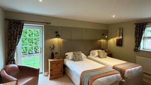 A bedroom with two beds, a chair, a nightstand, and a window with curtains. - New Farm Bed & Breakfast (Winsford)