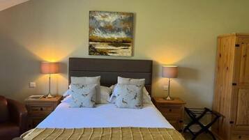 A bedroom with a bed, two bedside lamps, a wooden wardrobe, and a painting on the wall.