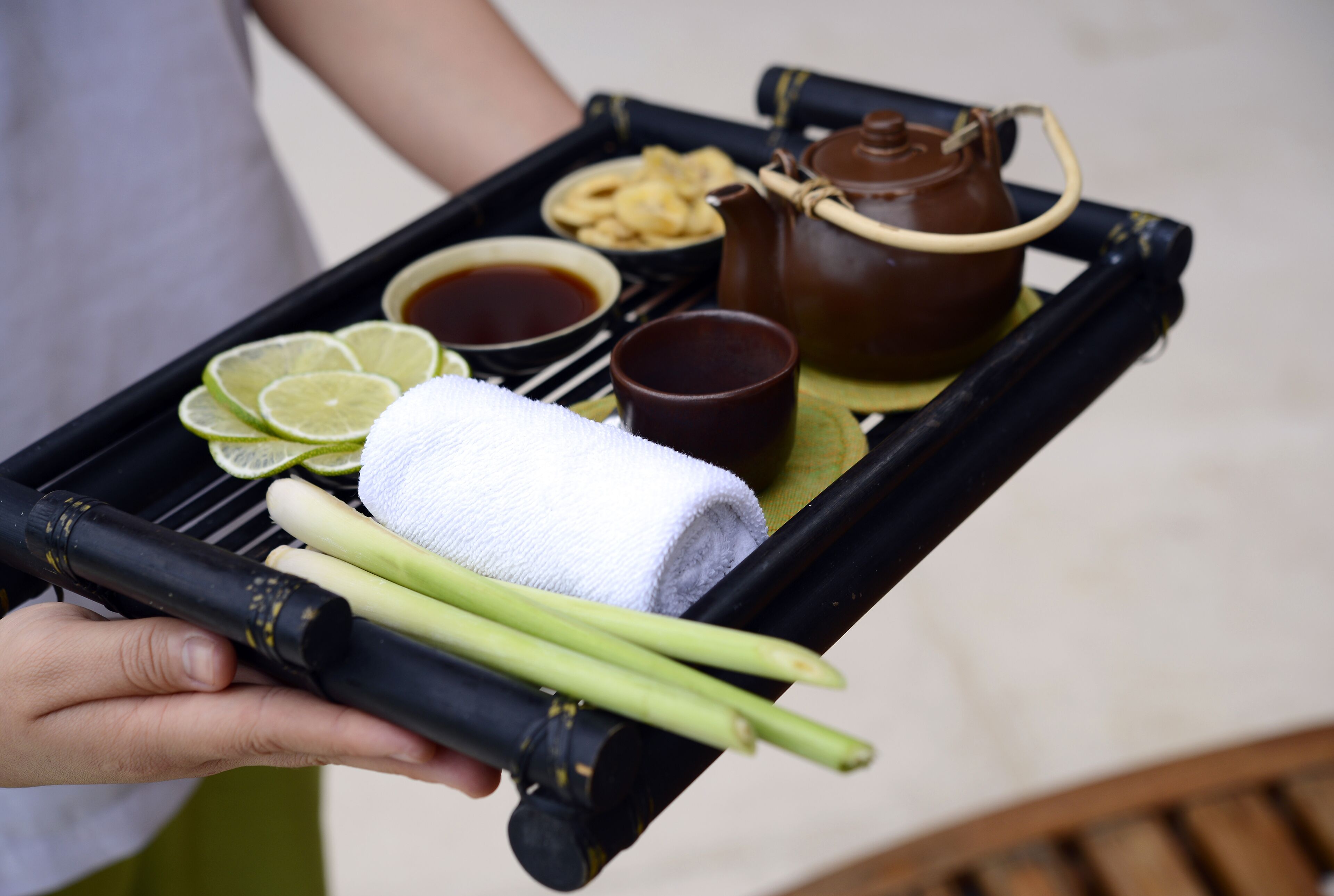 Una bandeja con tetera, tazas, rodajas de lima y cebollas verdes.