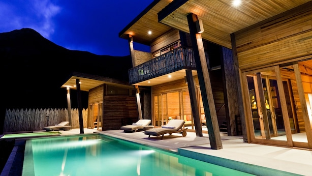 A modern resort with a swimming pool, wooden exterior, and a balcony with lounge chairs. - Six Senses Con Dao (Ho Chi Minh City)