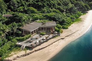 An aerial view of a beachfront property with a large building, a paved walkway, and a sandy beach. - Six Senses Con Dao (Ho Chi Minh City)