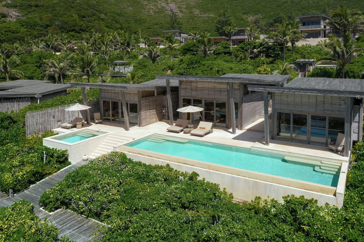 A modern resort with a large pool, outdoor seating, and lush greenery.