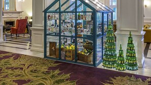 A lobby with a glass display case filled with bottles, a fireplace, and Christmas trees.