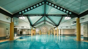 An indoor swimming pool with a high ceiling, skylights, and a central column.
