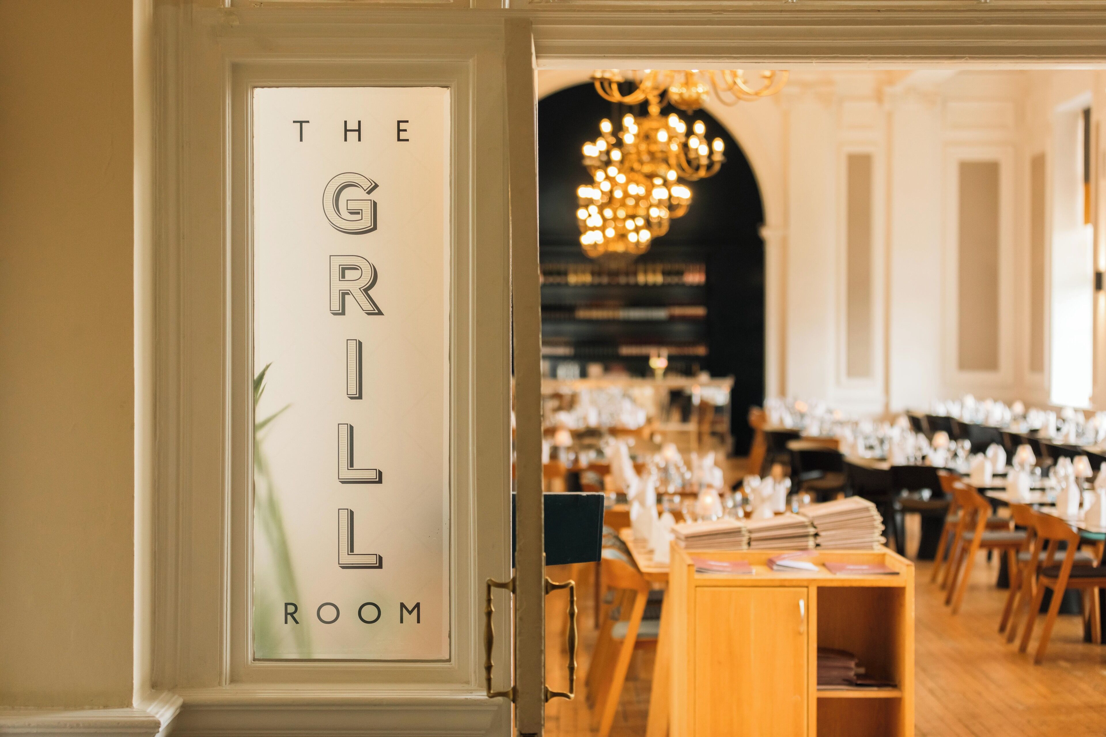 A restaurant interior with a sign reading 'THE GIRL ROOM' and a chandelier in the background.