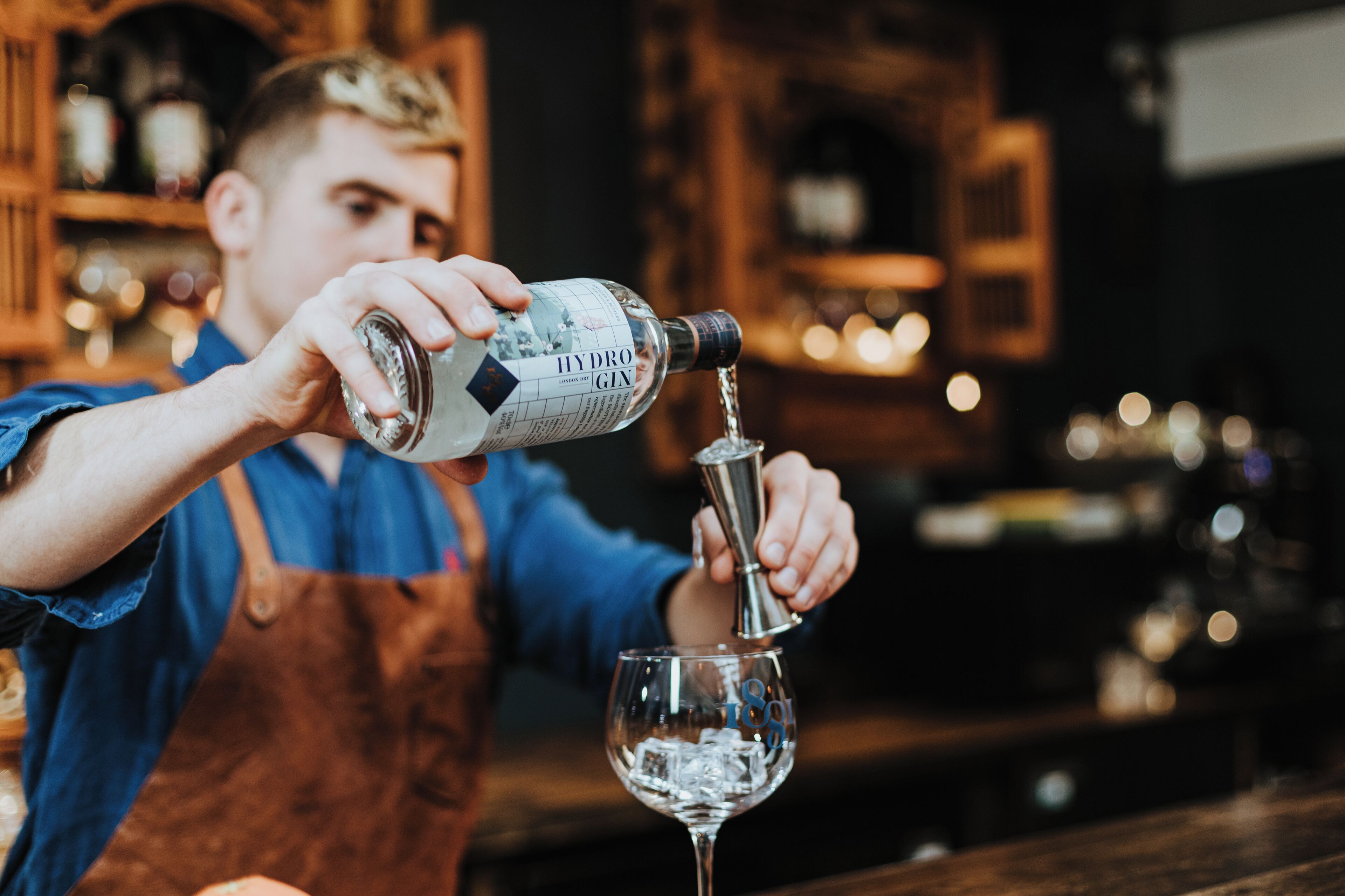 A person pouring a clear liquid from a bottle into a glass.
