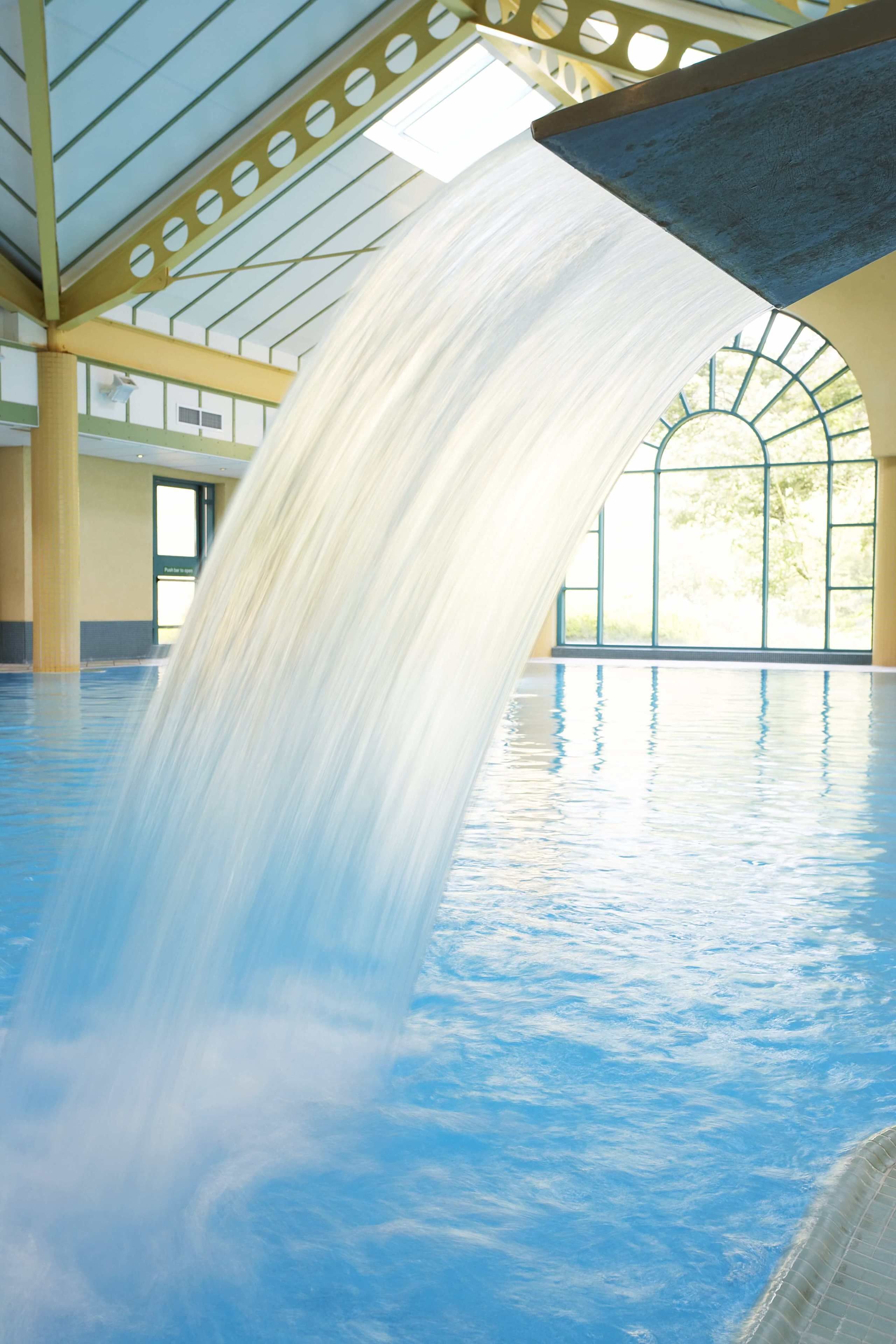 Une grande piscine intérieure agrémentée d’une cascade.