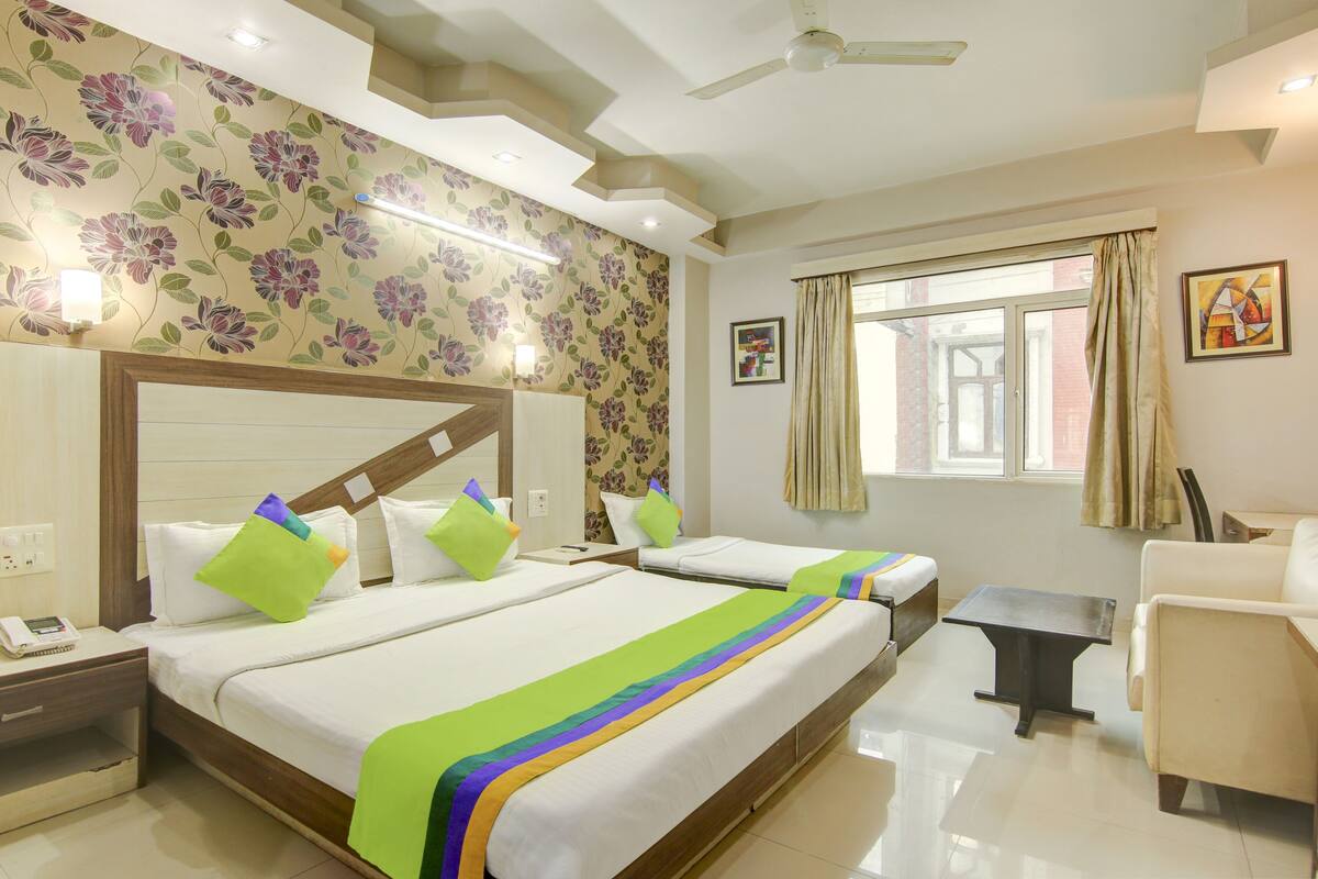 A hotel room with two beds, a nightstand with a phone, a desk, and a chair.