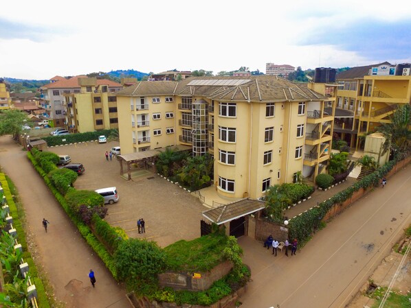 A multi-story building with a central courtyard, surrounded by greenery and a paved road.