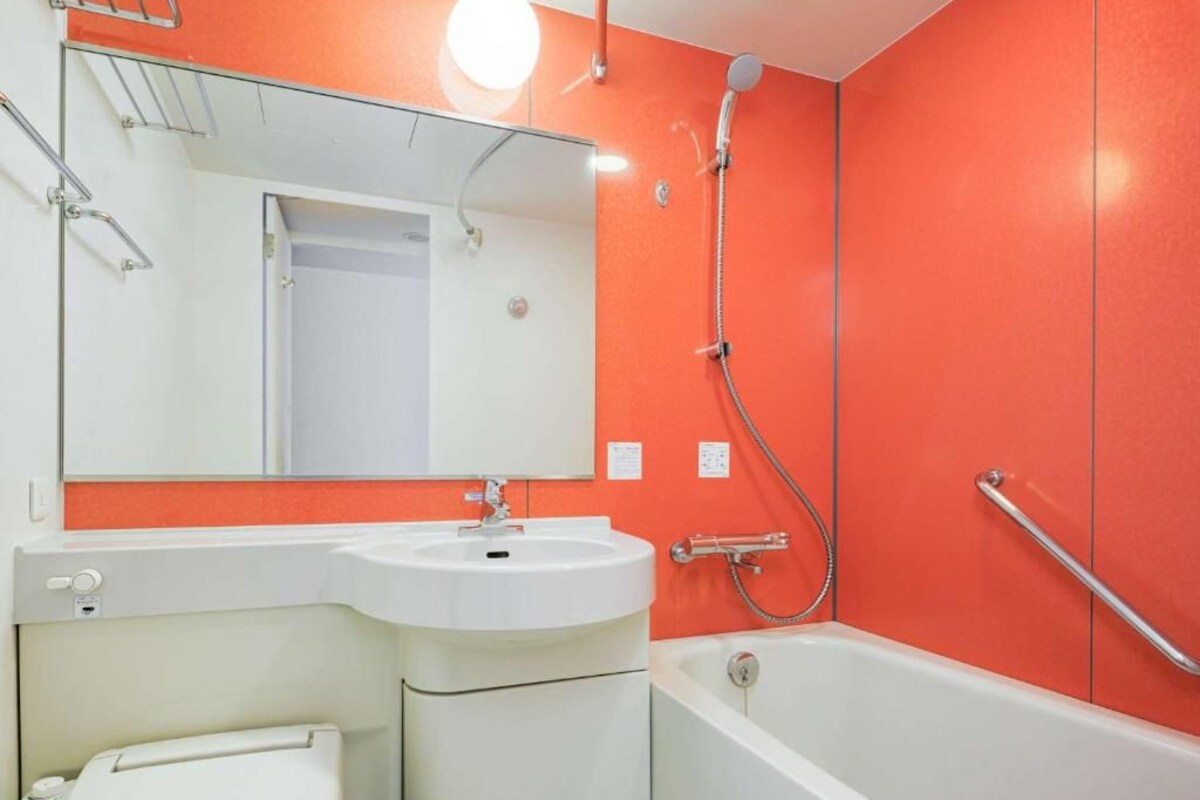 Une salle de bain avec un lavabo blanc, un miroir, une douche et une baignoire.