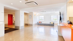 A spacious lobby with a reception desk, a seating area, and a red door.